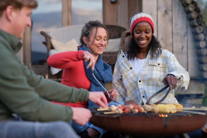 A group of people sitting around a barbecue whilst camping in Scotland 