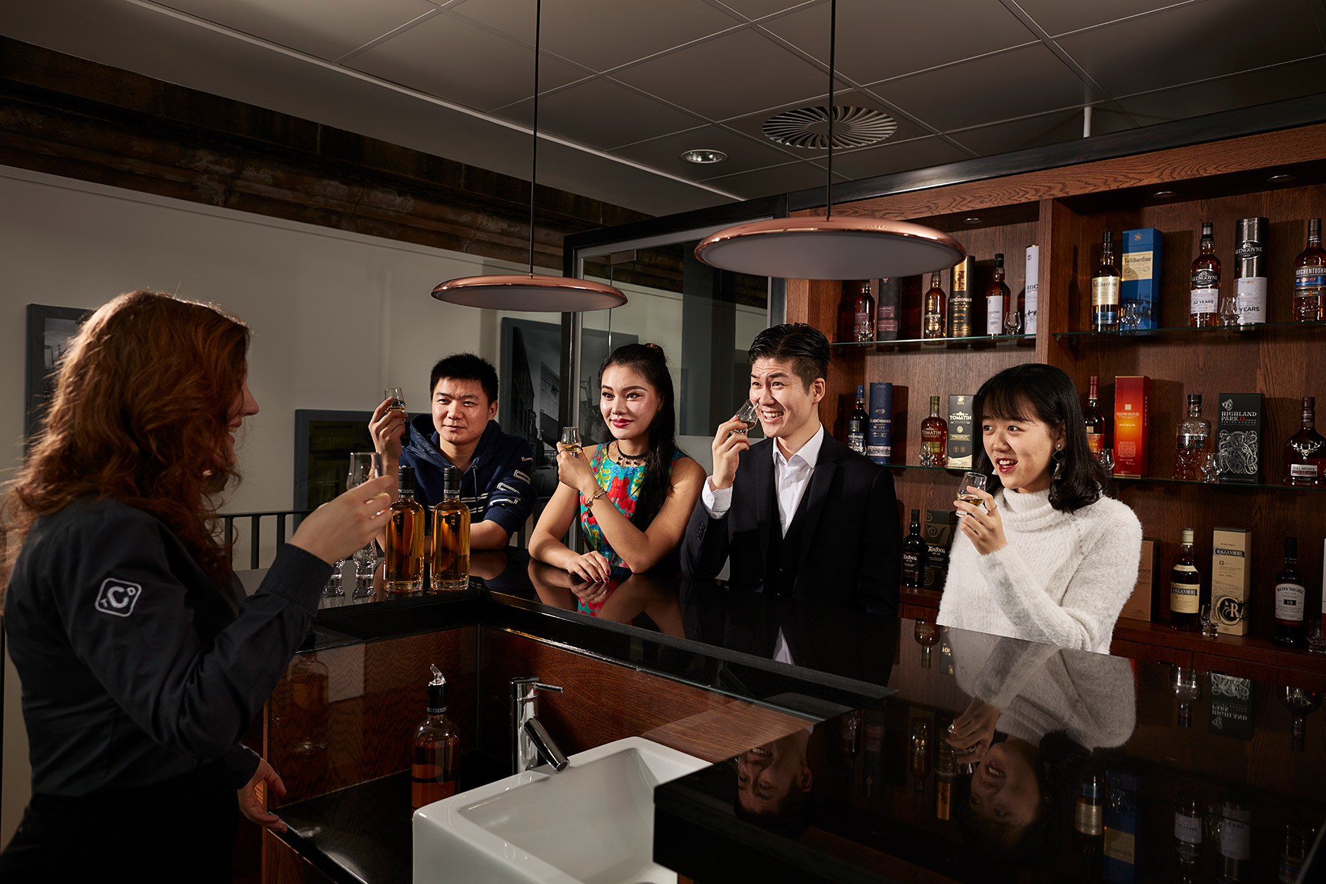 A group of people participating in a whisky tasting at a bar